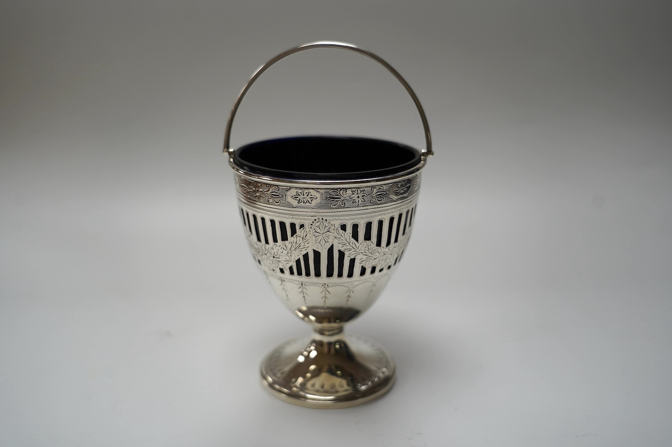 A George III pieced silver pedestal sugar basket, with blue glass liner, John Whittingham?, London, 1790, height 11.5cm. Condition - fair